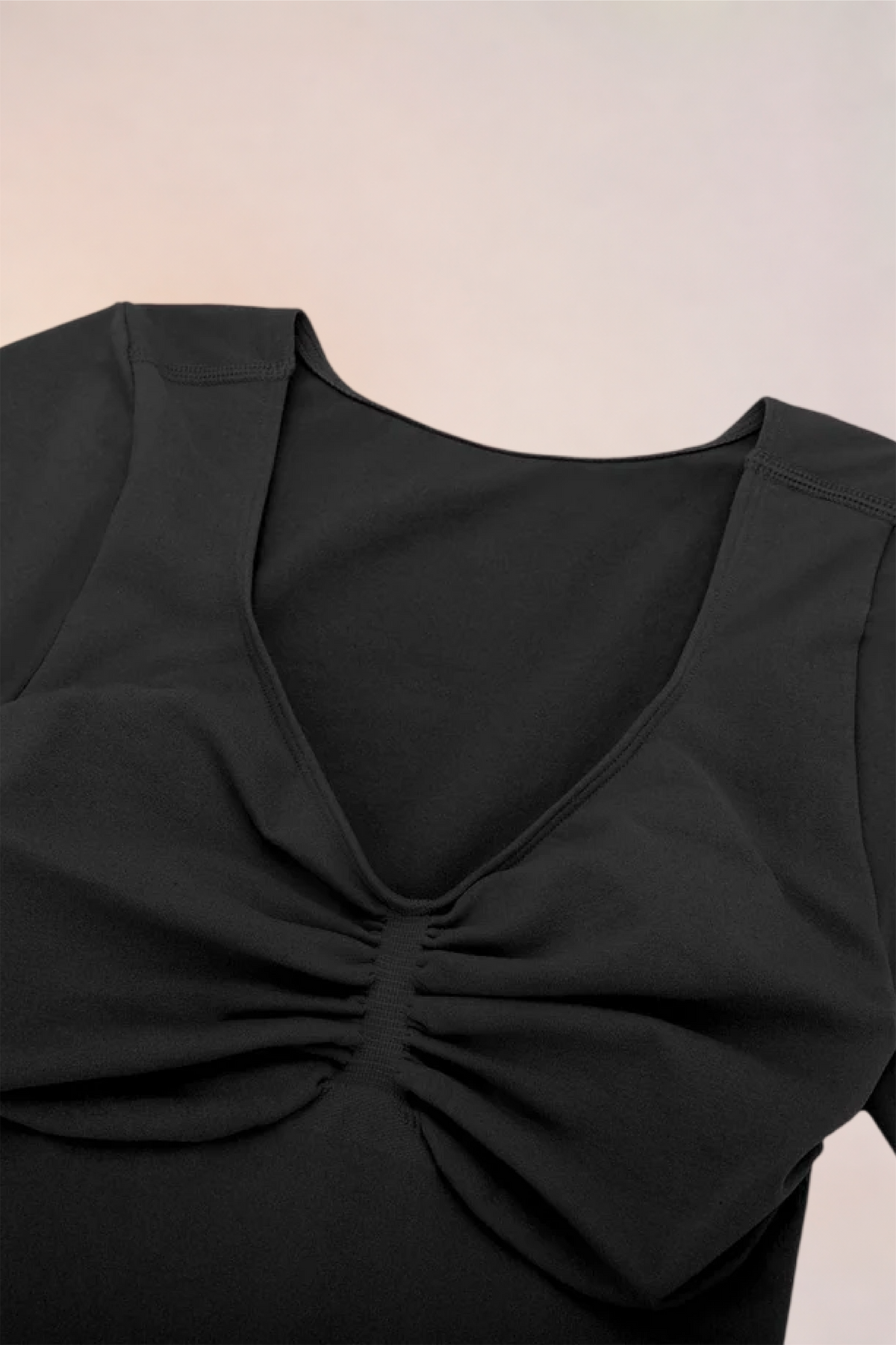 Flat lay of the Skinzform Contour Bodysuit in Noir showing the V-neckline and ruching