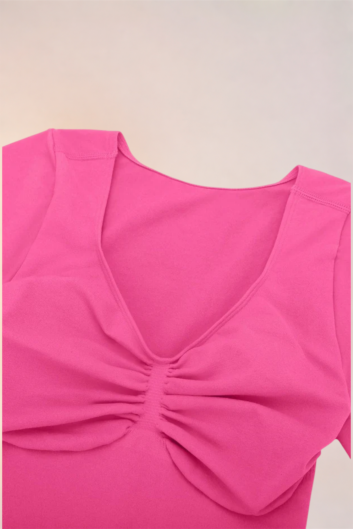 Flat lay of the Skinzform Contour Bodysuit in Rose showing the V-neckline and ruching