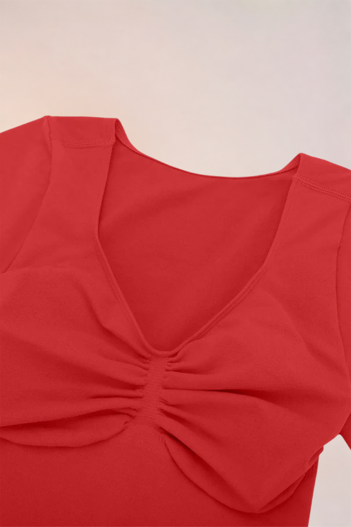 Flat lay of the Skinzform Contour Bodysuit in Rouge showing the V-neckline and ruching