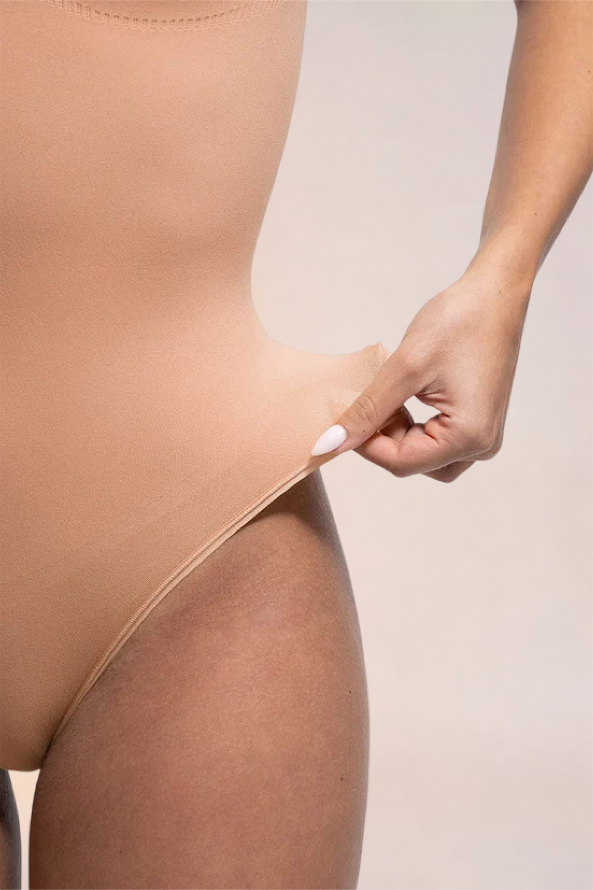 Skinzform Diamant Bodysuit in Nude - fabric stretched at the hip to show the give