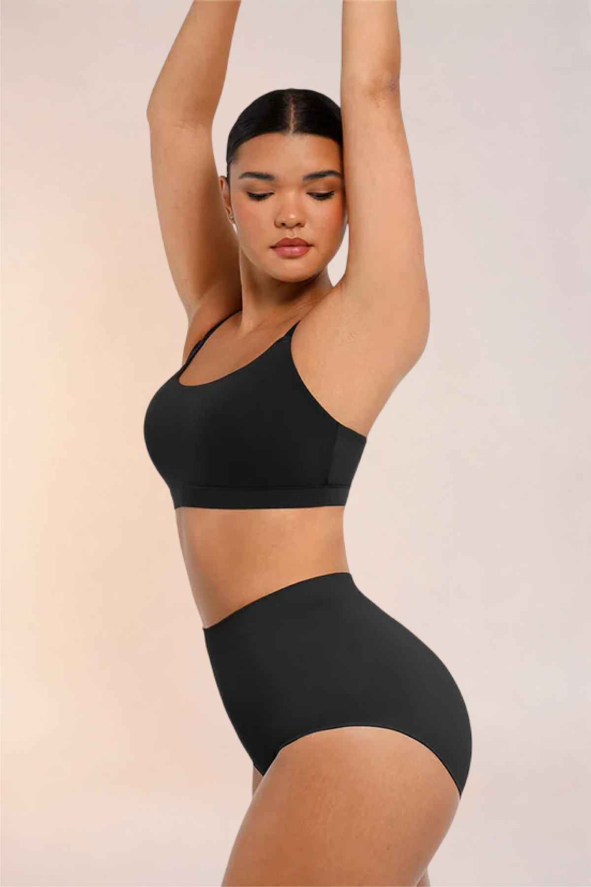 Skinzform Doux Bralette in Noir worn with matching briefs, side view with arms raised