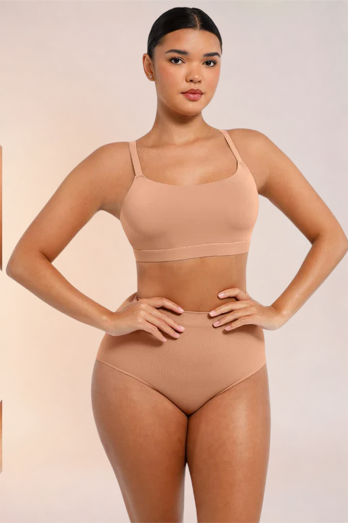 Skinzform Doux Bralette in Beige worn with matching high-waist briefs, hands at the hips