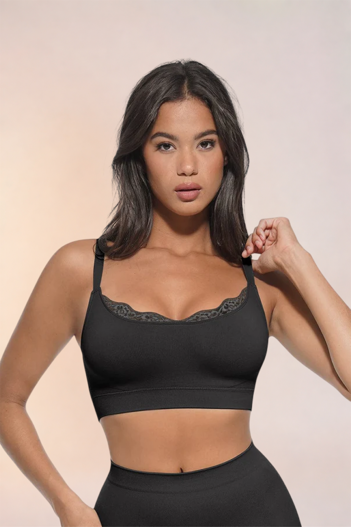Skinzform Scoop Bralette in Noir, front view on the model with a hand at the shoulder