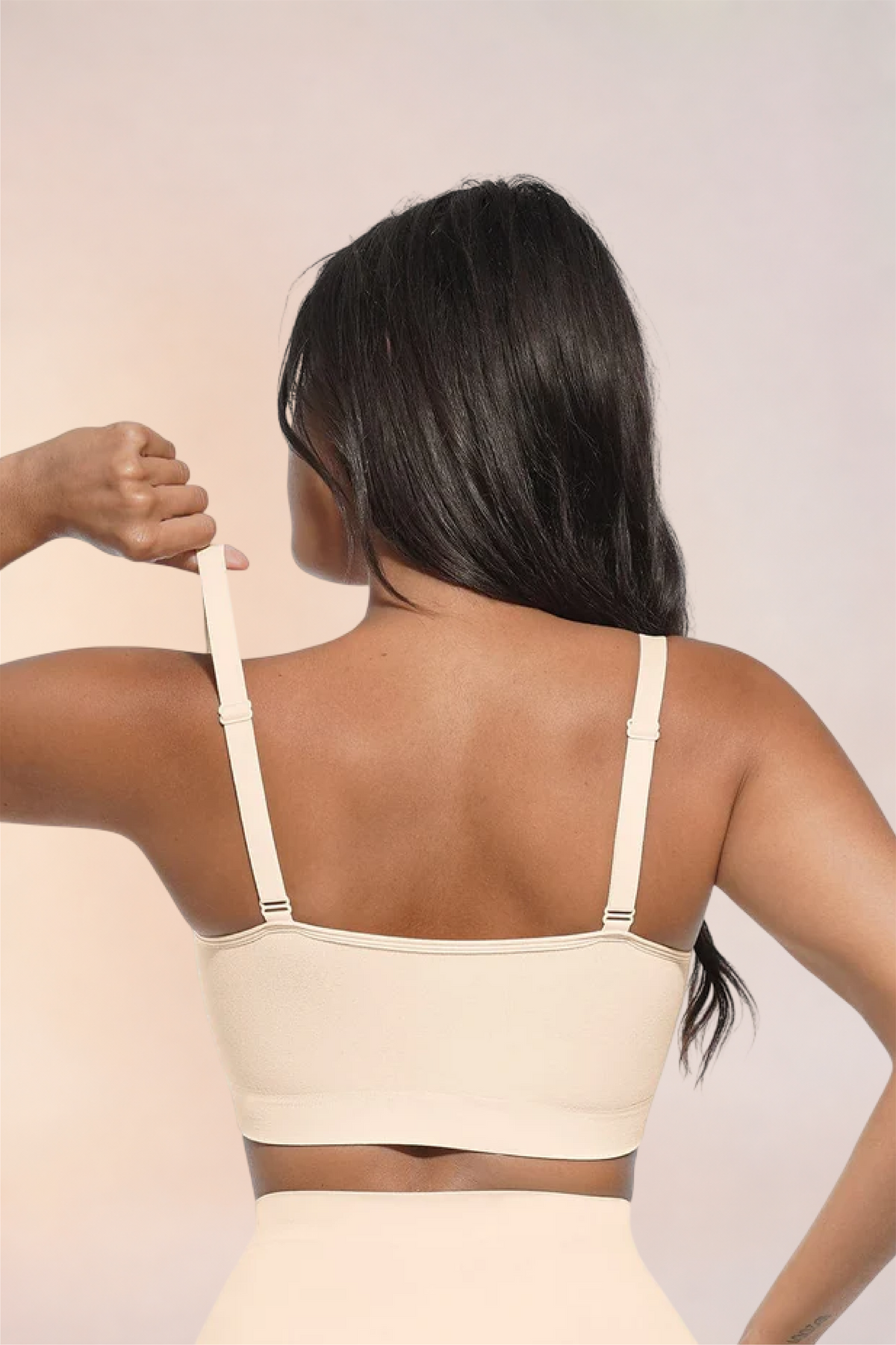 Skinzform Scoop Bralette in Nude, back view - model adjusting one strap
