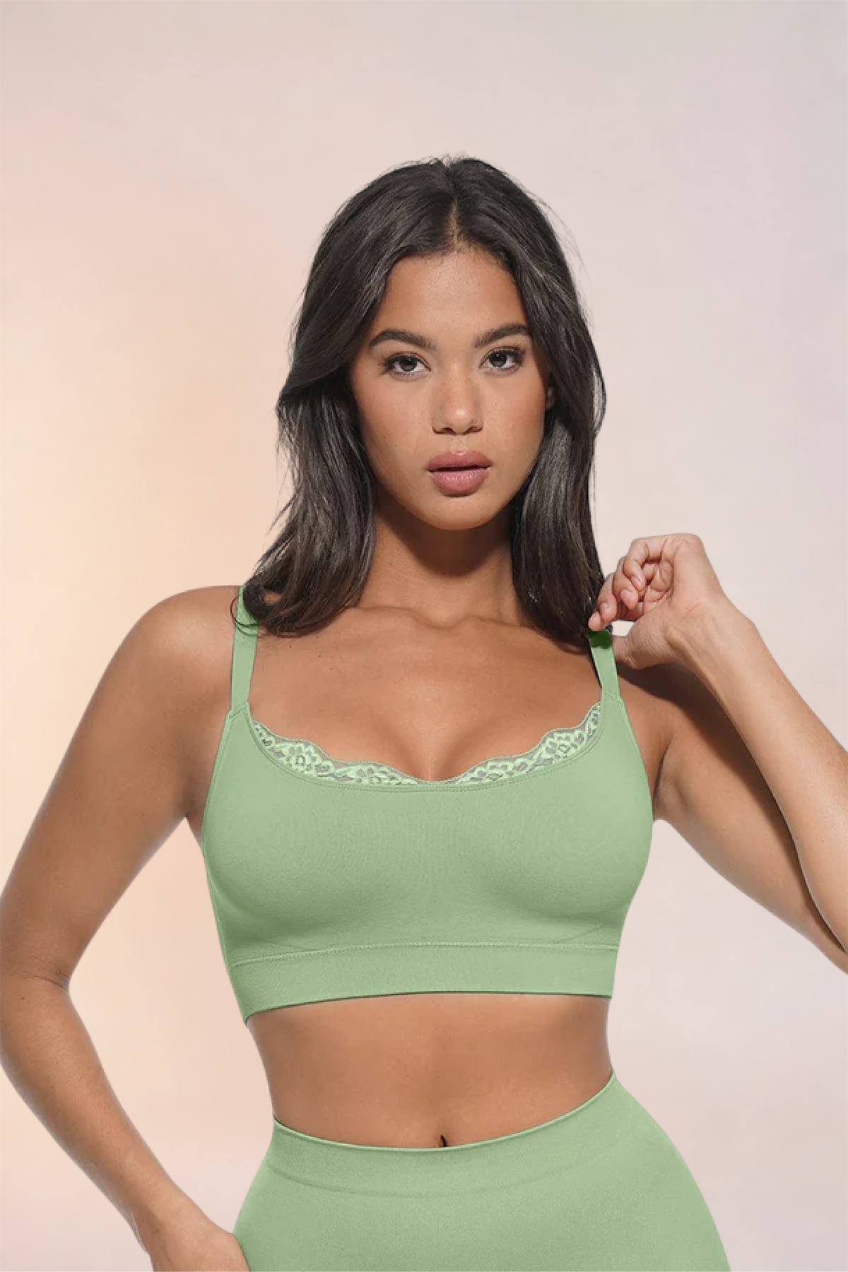 Skinzform Scoop Bralette in Sage - model adjusting one strap, front view