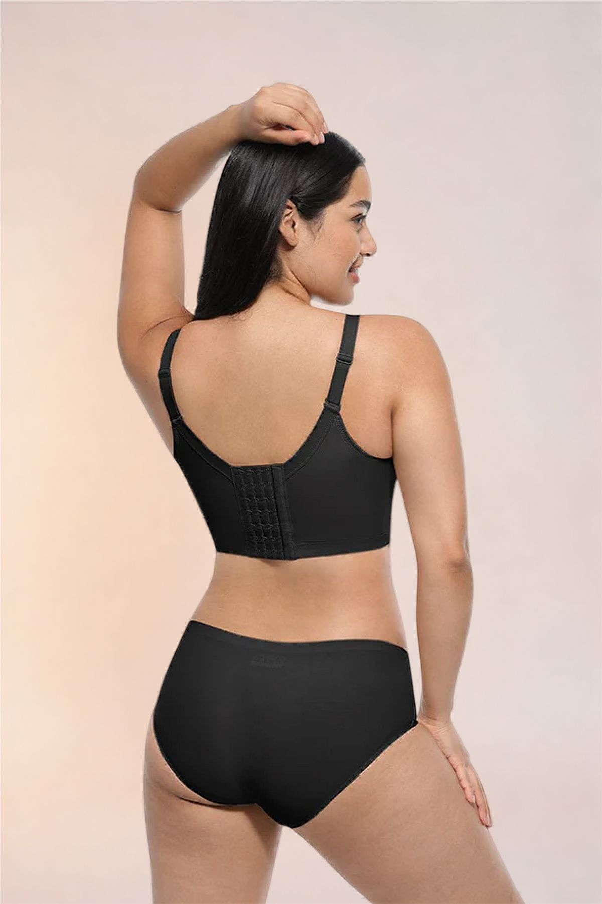 Skinzform Sculpt Bra in Noir, angled back view with a hand at the head